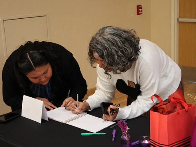 Colleagues sign a memory book at Joan's retirement party