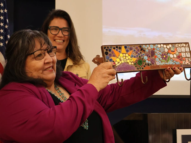 Joan raises a tile mosaic she received as a gift from the Udall Center