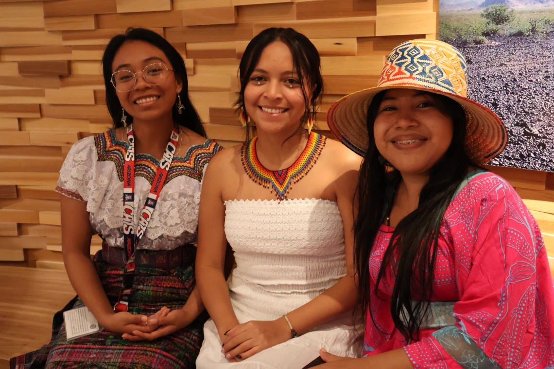 3 students pose on a bench against a wood-paneled wall at the Tohono O'odham Museum and Cultural Center