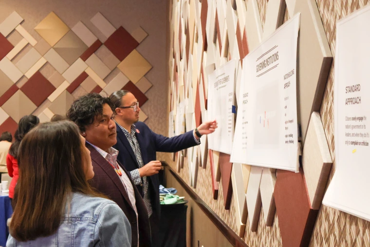 Attendees chat as they place markers on a chart on the wall.