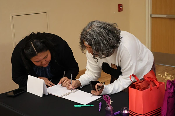 Colleagues sign a memory book at Joan's retirement party