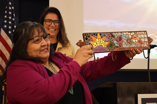 Joan raises a tile mosaic she received as a gift from the Udall Center