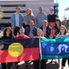 Aboriginal students on an Aurora Foundation U.S. Study Tour pose outside of NNI with Aboriginal and Torres Strait Islander flags